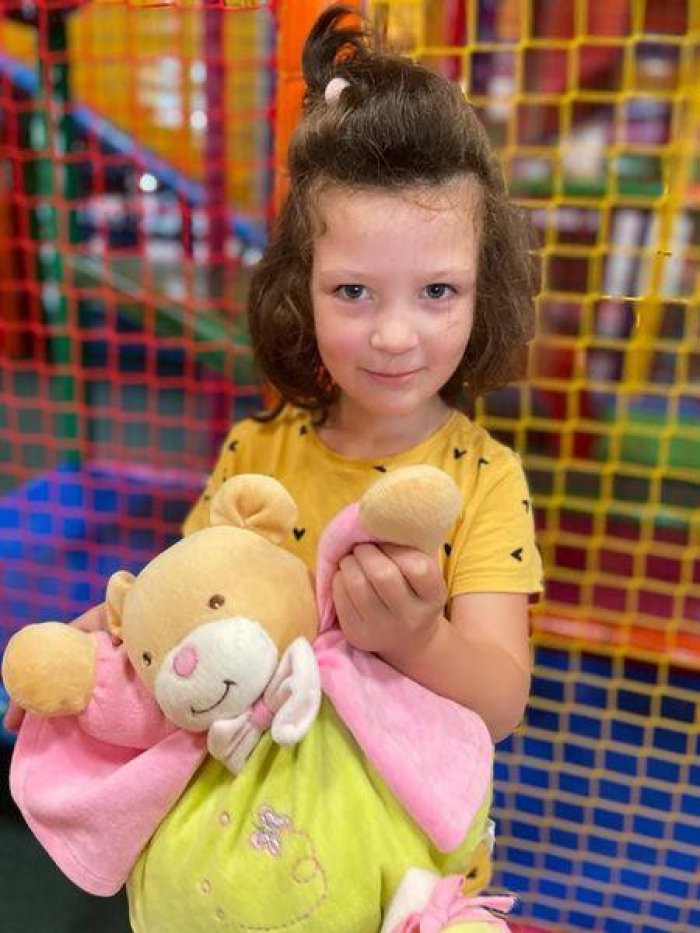 Uczennica w figloraju ze swoją maskotką pluszowym misiem.