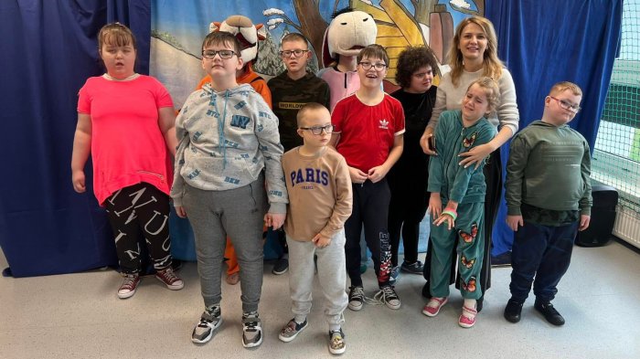 Uczniowie pozują do zdjęcia z maskotkami Kubusia Puchatka i Króliczka.