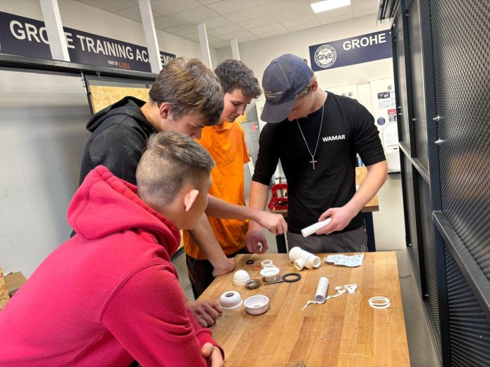 Uczniowie uczą się pod okiem starszych kolegów montażu rurek.