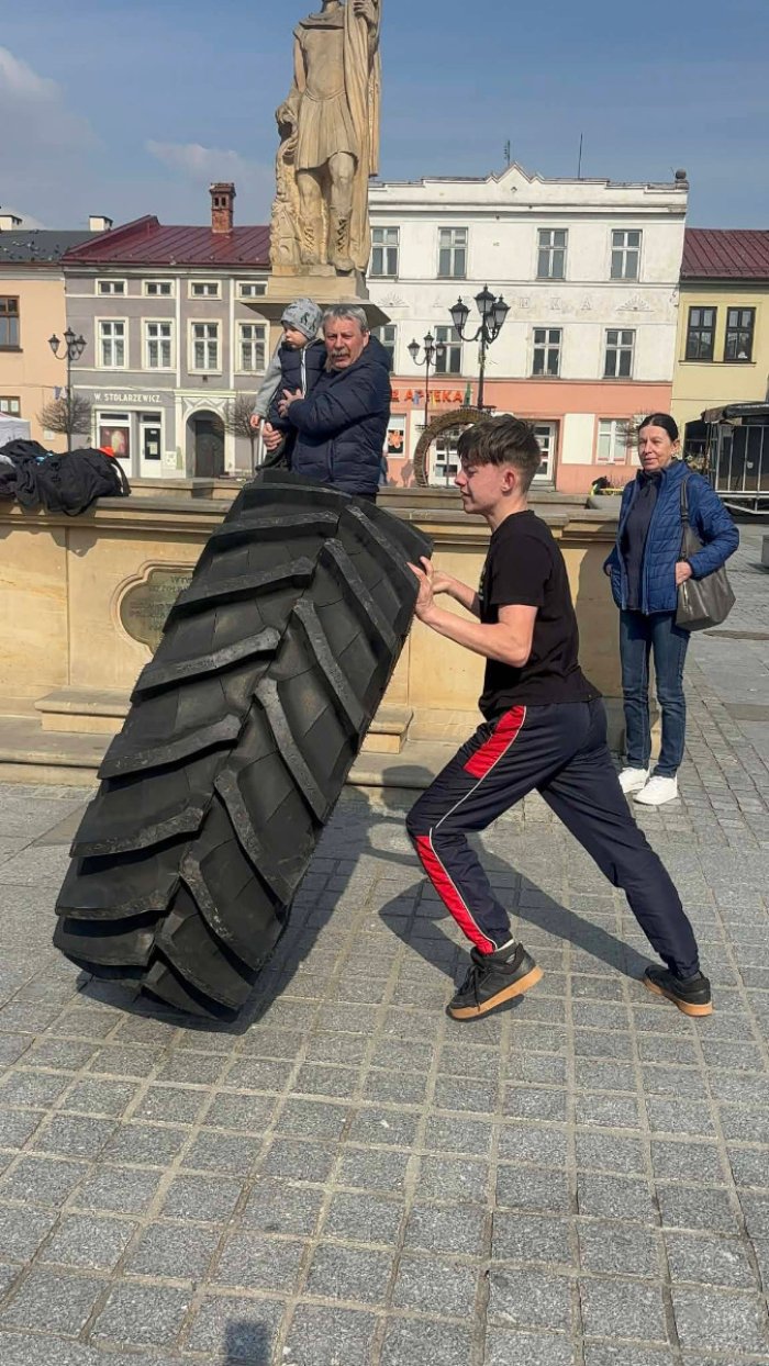 Uczeń klasy branżowej podnosi koło od traktoru na torze sprawnościowym.