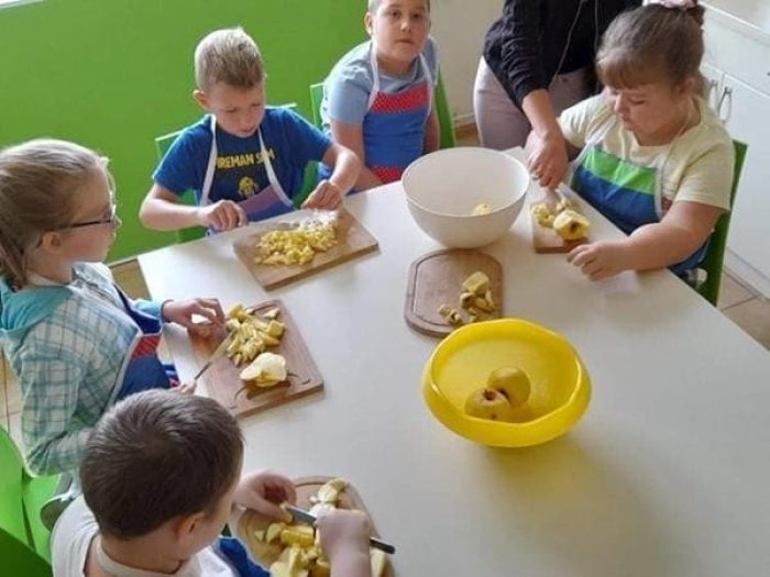 Uczniowie kroją jabłka.