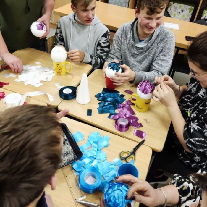 Podopieczni internatu wykonują bombki ze wstążki.