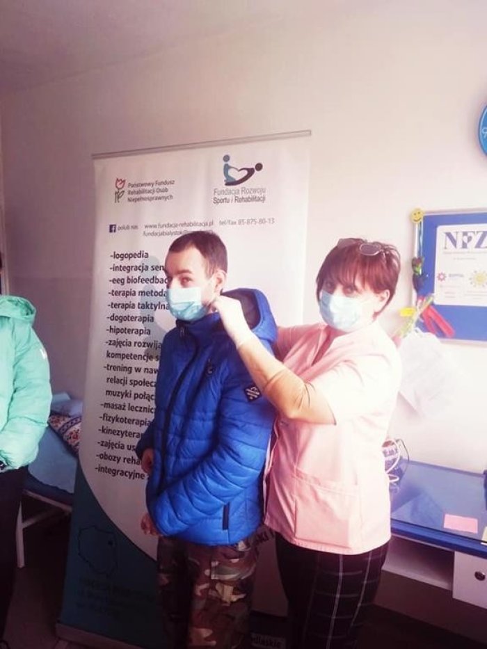 Pani pielęgniarka prezentuje w jaki sposób prawidłowo założyć maseczkę