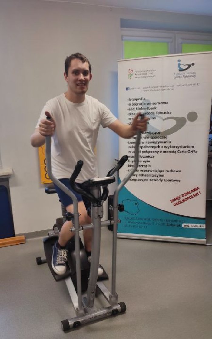 Uczeń ćwiczy na rowerku stacjonarnym.