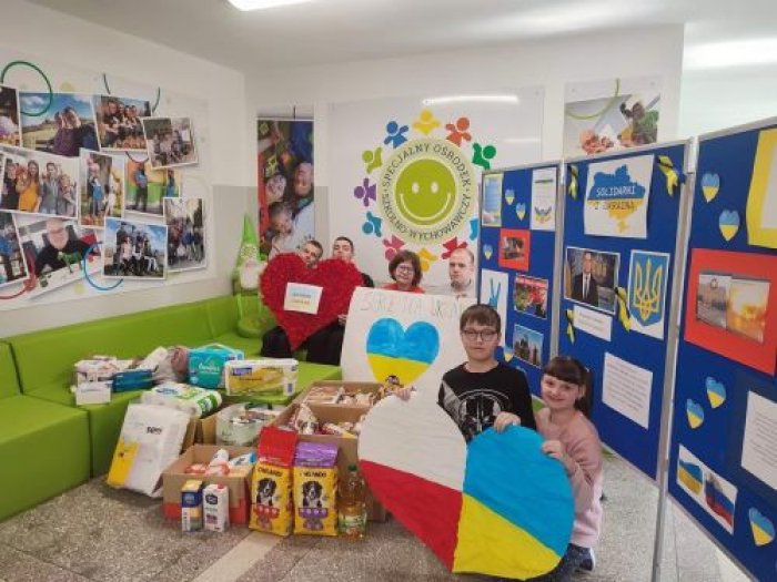 Uczniowie na tle zebranych rzeczy dla uchodźców z Ukrainy.