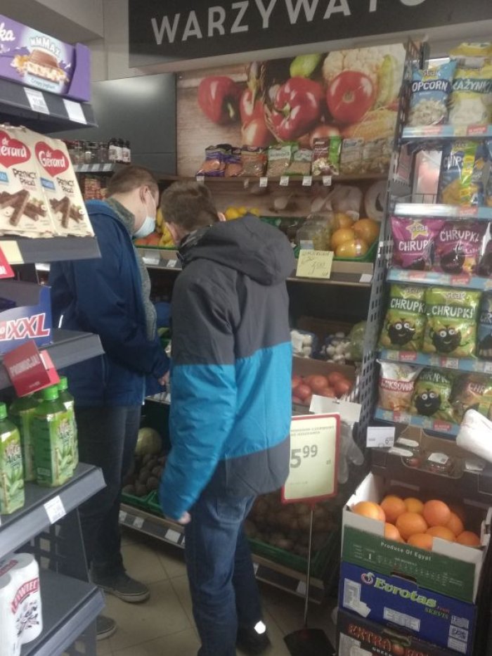 Uczniowie wybierają warzywa na stoisku warzywnym.