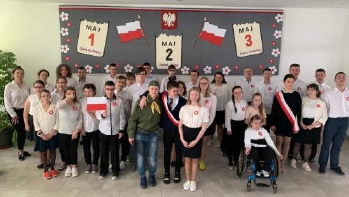 Uczniowie ubrani na galowo pozują do pamiątkowego zdjęcia.