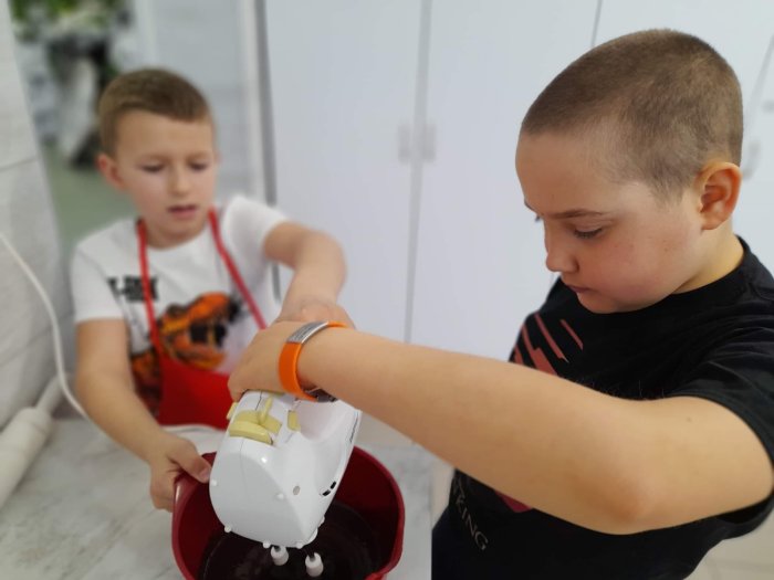 Uczniowie miksują za pomocą miksera składniki na ciasto czekoladowe.