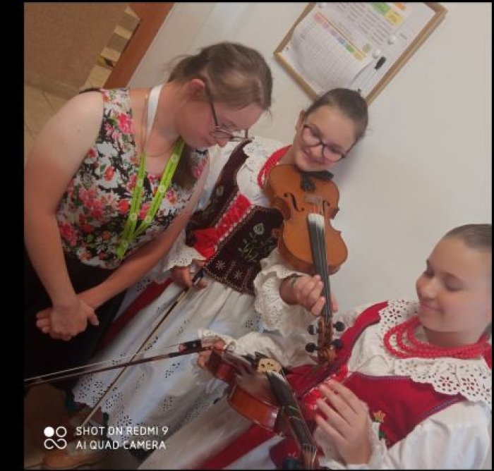 Dziewczęta w strojach góralskich prezentują uczestnikom warsztatów regionalnych budowę skrzypiec.