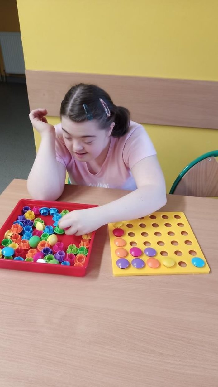 Uczennica wkłada klocki do otworów.