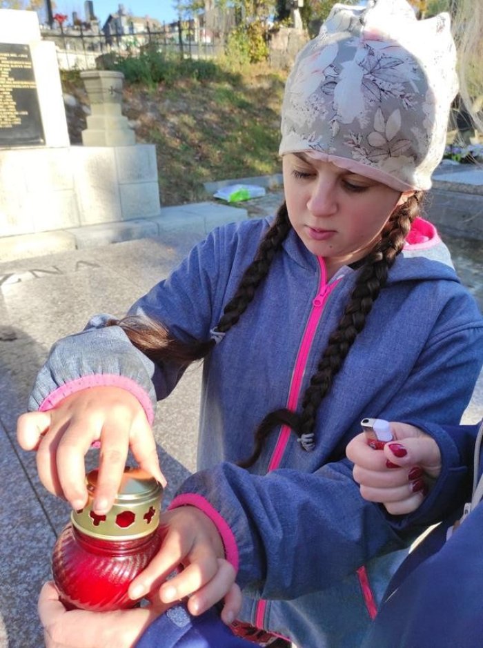 Uczniowie zapalają znicze.