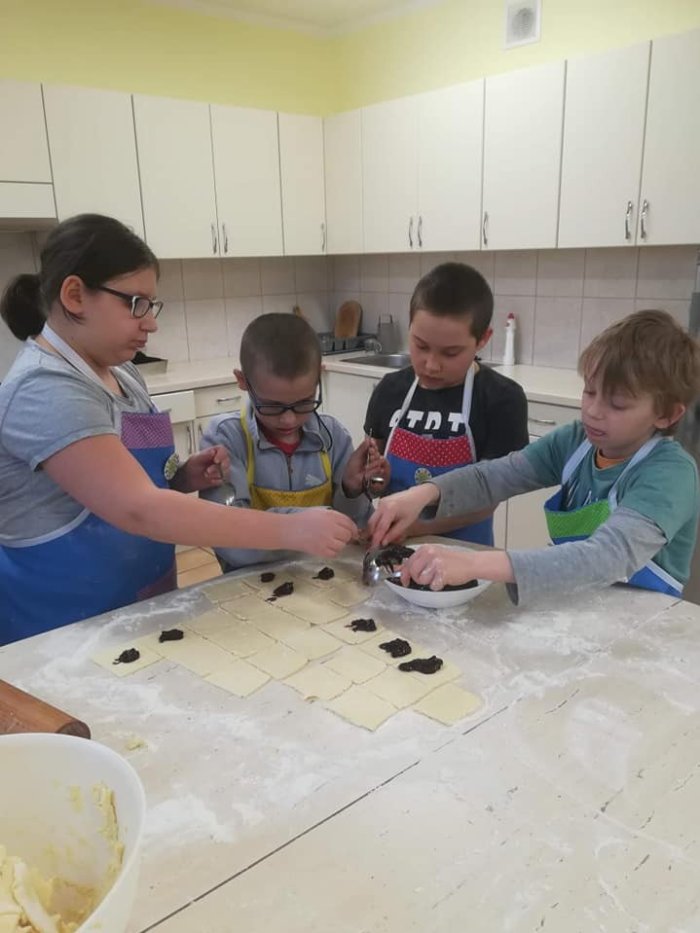 Uczniowie nakładają marmoladę na rogaliki.