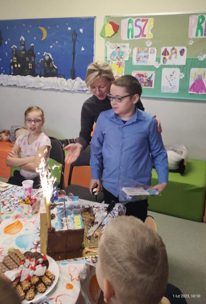 Pani dyrektor wraz z Kubusiem zachwycają się fontanną świetlną na torcie urodzinowym.