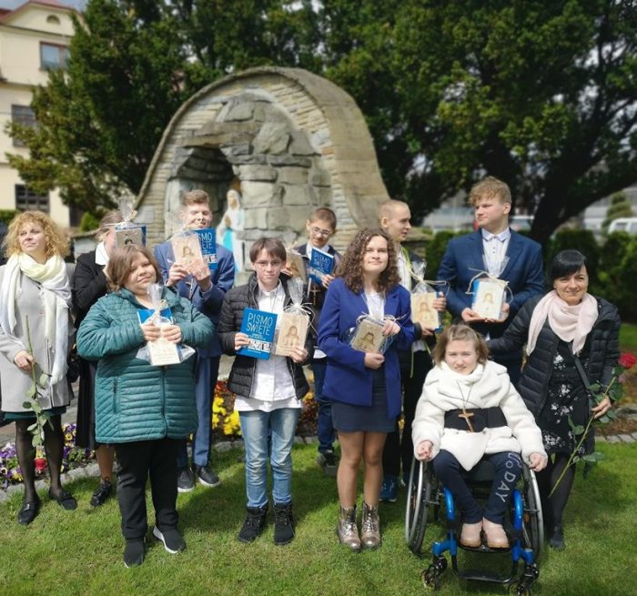 Uczniowie, którzy otrzymali bierzmowanie pozują do zdjęcia przy figurze Matki Bożej.